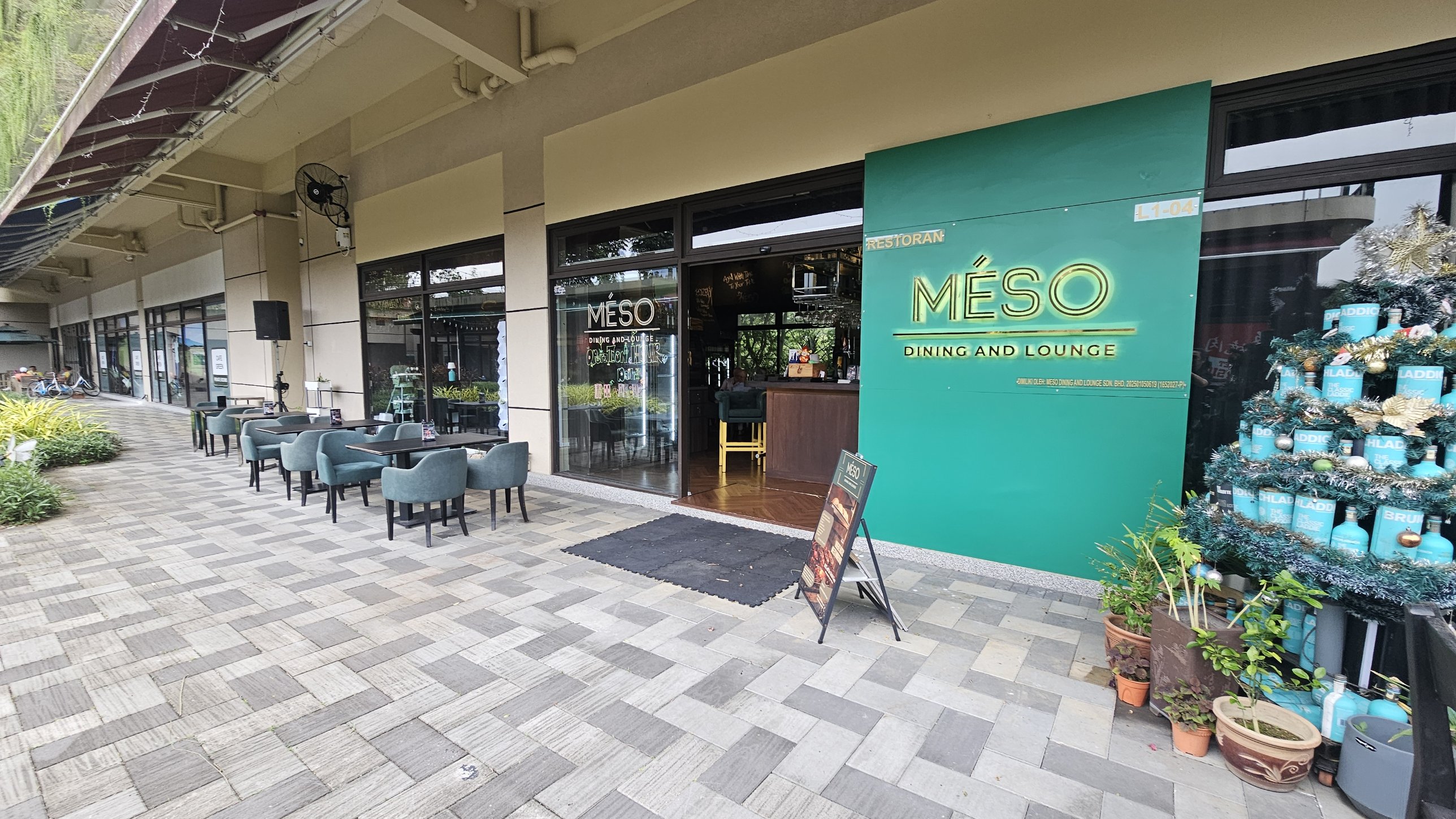 The MÉSO Dining and Lounge entrance, with its green sign and terrace tables